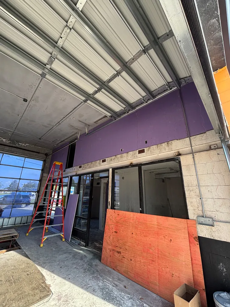 Purple moisture-resistant drywall installation above garage door at car wash in Winter Park, FL